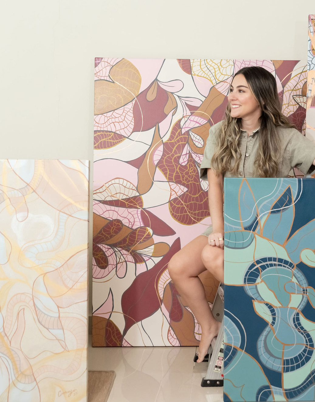 Carolina Jaen smiling with 3 of her works